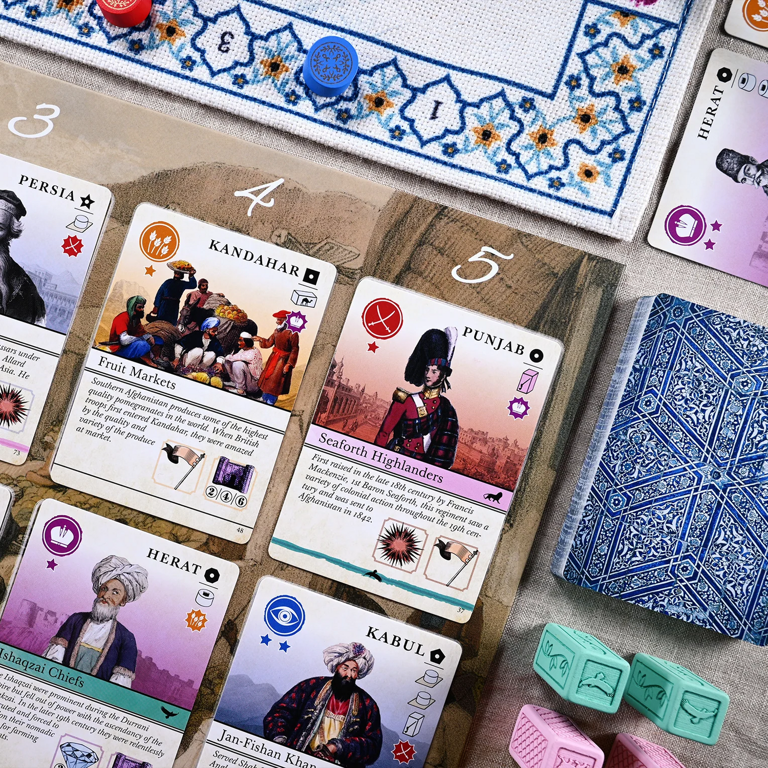 Pax Pamir: Second Edition – nærbillede af kort fra kortrækken med illustrationer af historiske personer og en markedsscene